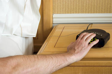 A man pressing the snooze button on an alarm clock.