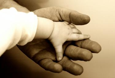 Baby hand on top of a big hand - God