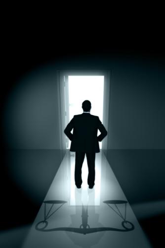 Man standing in front of door with light coming out and scales on the floor