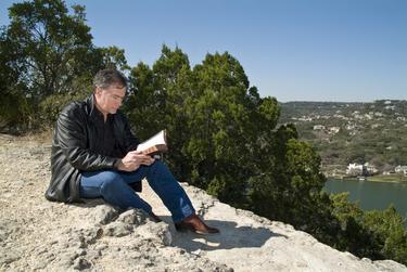 A man reading a Bible sitting outside.
