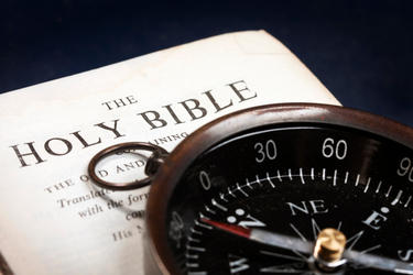 A compass on top of a Bible.