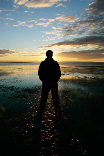 A silouette of a man looking at a sunset.