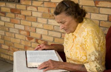 Older woman reading bible on a table - Understanding God