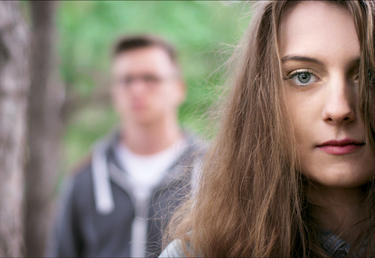 A young couple - woman in the foreground, man in the background blurred.