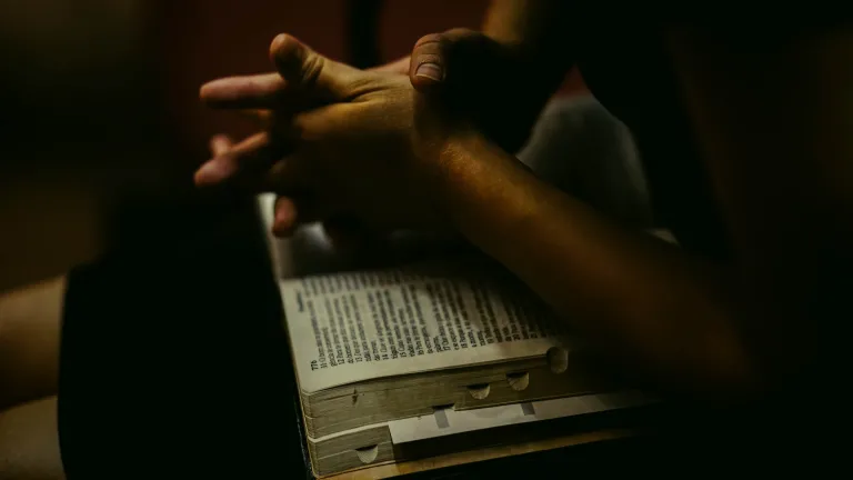 Christ puts none above another in the way that He tells the parable of the Good Samaritan, challenging the human tendency towards prejudice. He powerfully illustrates that it’s not who you are, or what you know, but what you do that is essential. A person with an open Bible on their lap.