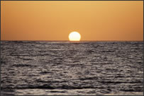 The sun setting over the ocean horizon.