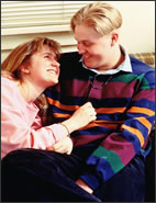 A teenage boy and girl looking at each other.