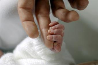 Infant hand grasping adult finger - What is the Value of a Life?