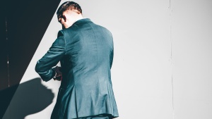 A man walking looking at his wrist.