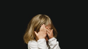 a child covering her face with her hands