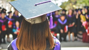 a woman's head wearing a graduation cap as she faces a crowd