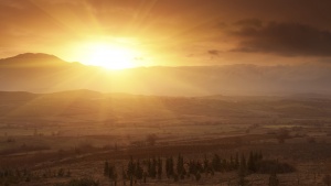 A sunrise coming over a mountain top lighting up the valley below.