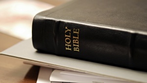 A Bible sitting on top of some notebooks and paper.