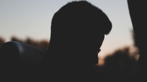 A silhouette of young man sitting in a bus.