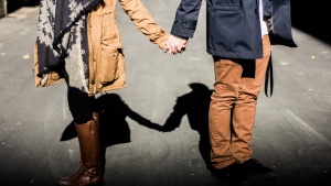 A young couple holding hands while walking.