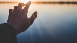 A hand reaching out over water. 