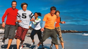 Young adults running on the beach.