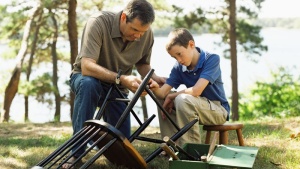 A father and son repairing a broken chair together.