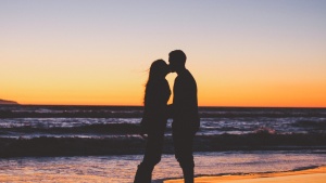 Husband and wife kissing on the beach.