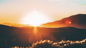 Sun rays shining over hills.