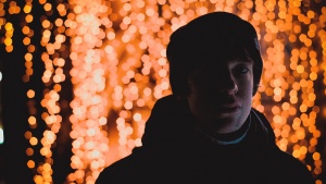 A young man standing in front of red lights.