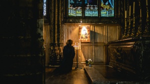 A woman praying to a painting hanging in a church.