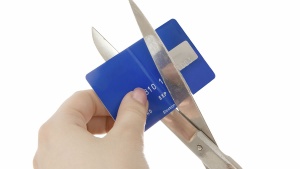 A person cutting a credit card with a pair of scissors.