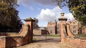 A big gate surrounding a large brick house.