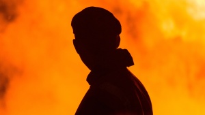 A silhouette of a man with smoke and flames around him.