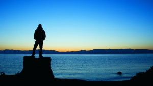 Silhouette of a man looking out over a body of water.