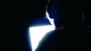 A man looking at a computer screen in a dark room.