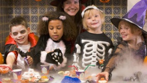 A mom and four kids eating Halloween treats.