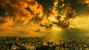 Sun rays shining through clouds on a city.