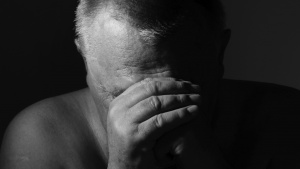 An old man with his head resting on his hands as if he was praying.