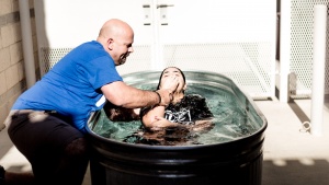 A woman being fully submersed in water during baptism.