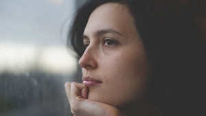 An upclose photo of woman's face looking out a window.