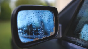 A car's side mirror cover with rain drops.