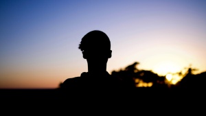 A shadow of young man looking towards the sunset.