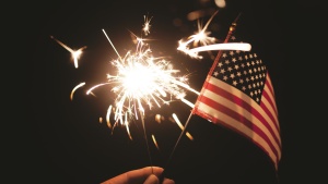 A person holding a sparkler and a small American flag.