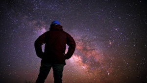 A person staring at the night sky filled with stars.