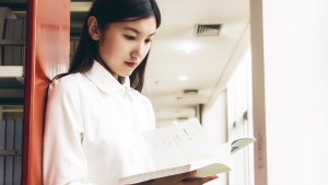 A woman looking at a book in a library.