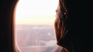 A young women looking out the window of an airplane. 