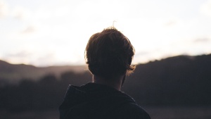 A young man looking at a sunset.