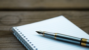 A writing pen on top of spiral bound notebook.