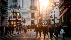 People walking a crowded city street and sidewalk.