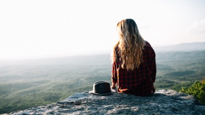 A young woman sitting on the edge of a rock.