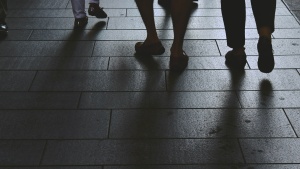 People walking a sidewalk. All you see is their legs and feet.