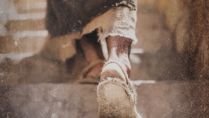 A person wearing sandals walking about dusty steps.