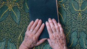 An older woman's hands resting on top of a Bible.