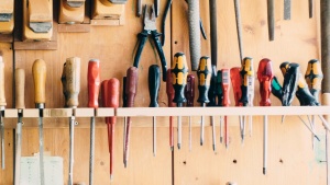 A workbench wall with many types of screwdrivers hanging. 